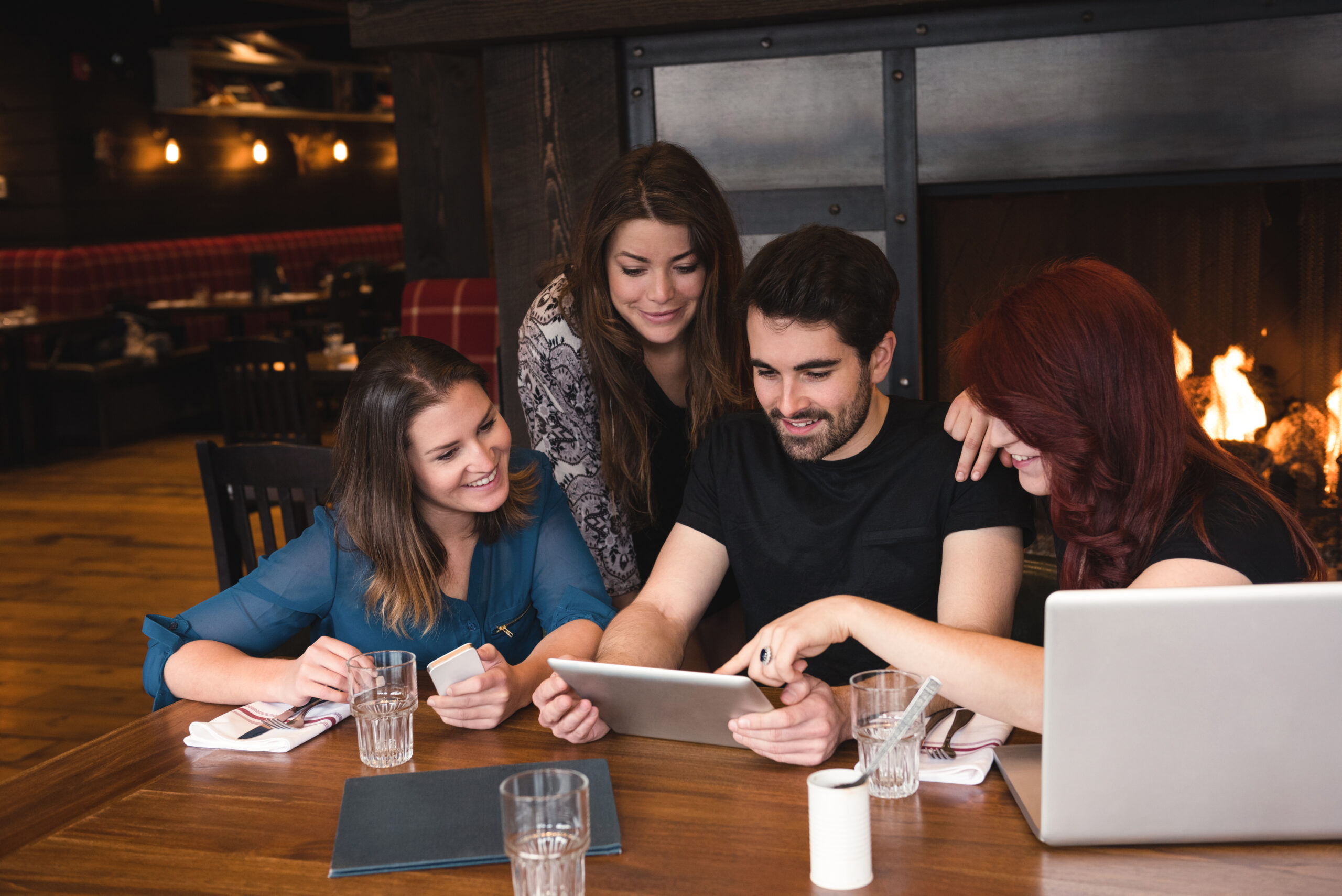 Three girls and one boy looking at a tablet screen together